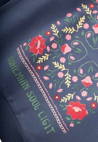 Tessuto blu navy con ricami floreali colorati in rosa e rosso, con accenti verdi. Testo "BOHEMIAN SOUL CIGIT" in verde nella parte inferiore.