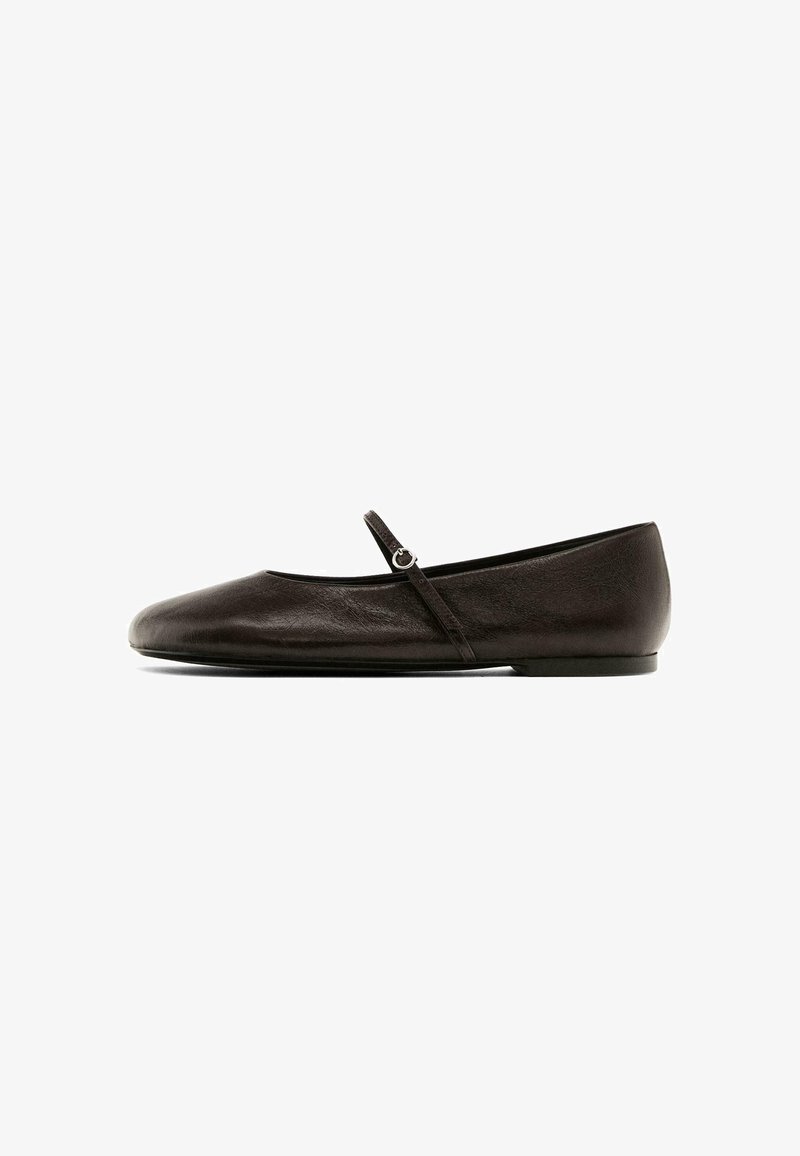 Chaussure en cuir noir mate avec un bout rond, dotée d'une petite sangle avec une boucle en argent pour un maintien sécurisé, texture lisse.