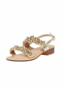 Sandal in metallo dorato con tacco basso a blocco, caratterizzata da cinturini decorati con grandi gemme decorative e design aperto sulla punta.