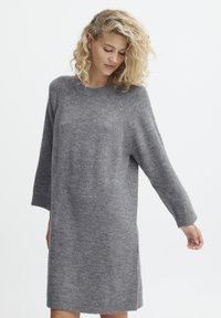 Rochie tricotată gri cu decolteu rotund, mâneci trei sferturi și croială lejeră. Textură netedă și un model subtil melanj.