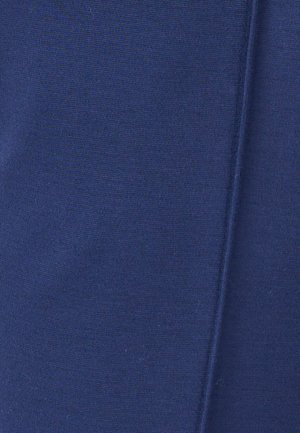 Tessuto blu con una cucitura visibile che corre verticalmente, mostrando una texture a coste fine e una leggera piega sul lato destro.