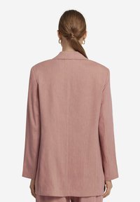 Ljusrosa blazer med avslappnad passform, långa ärmar och enkla snedskurna revers. Har ett mjukt, något texturerat tyg.