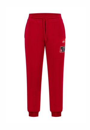 Pantalones de chándal rojos de algodón, con una cintura y puños elásticos, y una etiqueta de parche lateral. Textura suave, diseño casual.