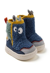 Botas infantiles que presentan una combinación de tejido azul esponjoso y texturas suaves, detalles en ante gris claro, ribete amarillo y un diseño de ojos juguetón.