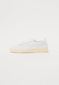 Zapatillas con parte superior sintética blanca, diseño perforado, cordones planos y suela de goma color crema. Presentan un logotipo en el talón y en el lateral.