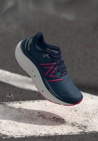 Hardloopschoen in marineblauw met roze accenten. Voorzien van een bovenwerk van mesh, een lichte zool en een gestructureerd oppervlak. Merkvormgeving aan de zijkant en op de tong.