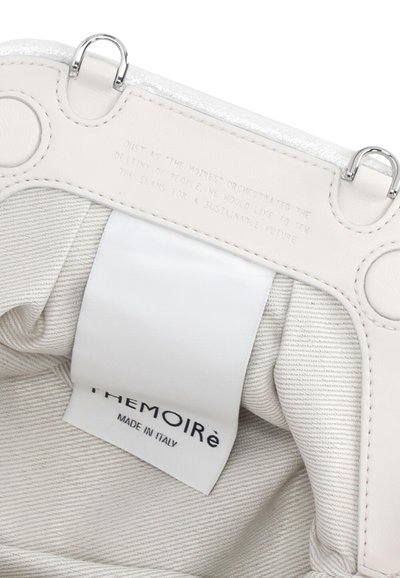 Interno di una borsa in pelle bianca con una texture liscia e una leggera lucentezza, caratterizzato da un'etichetta visibile con la scritta "THEMOIRé MADE IN ITALY." Accenti in hardware argentato.