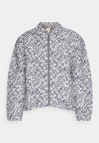 Vatteret jakke i marineblå og hvid med en tekstureret overflade, lynlås foran og en opretstående krave. Har en afslappet pasform og kort længde.