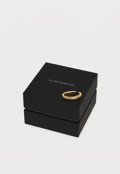 Μαύρο κουτί κοσμημάτων με ασημί κείμενο "ALAN CROLETTI" στο καπάκι, με χρυσό ανοιχτό δαχτυλίδι με μικρές ενσωματωμένες πέτρες.