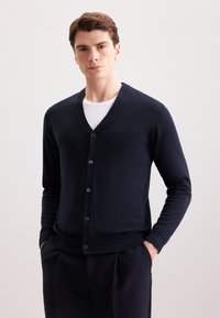 Cardigan navy realizzato in morbido tessuto a maglia, con scollo a V, cinque bottoni blu e polsini e orlo a costine aderenti.