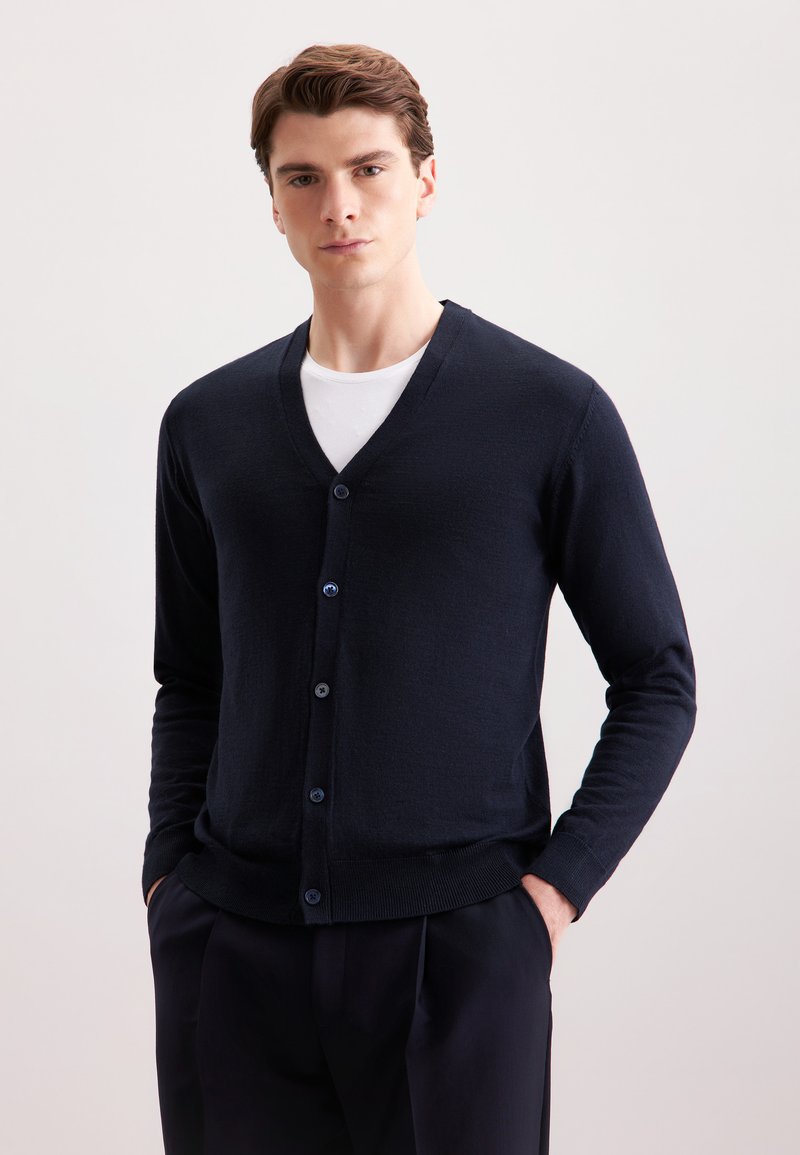 Cardigan navy realizzato in morbido tessuto a maglia, con scollo a V, cinque bottoni blu e polsini e orlo a costine aderenti.