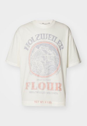 Valkoinen ylisuurikokoinen T-paita, jossa on haalistunut vintage-tyylinen myllyn graafinen kuva ja tekstit "Holzweiler Flour" ja "Net wt. 5 lbs." edessä.