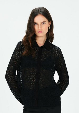 Blusa in pizzo nero con maniche lunghe. Presenta un colletto e chiusura frontale con bottoni. Il motivo in pizzo intricato aggiunge texture al capo.