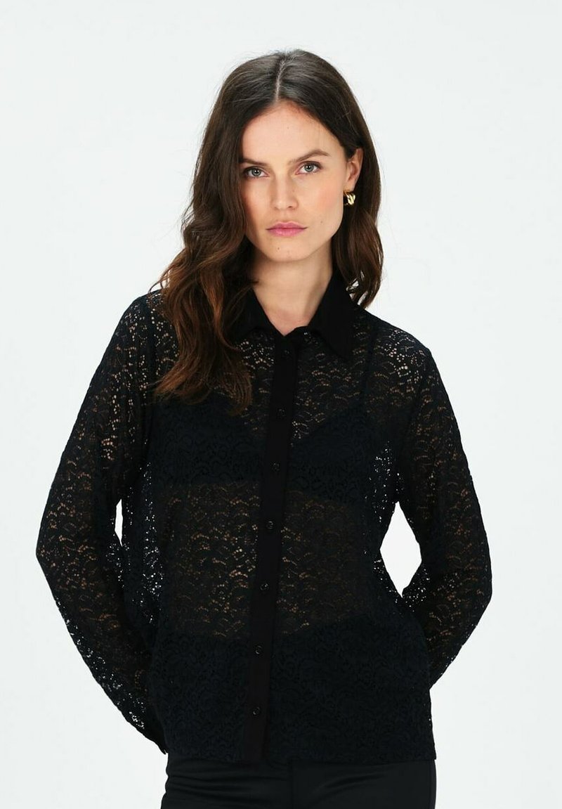 Blusa in pizzo nero con maniche lunghe. Presenta un colletto e chiusura frontale con bottoni. Il motivo in pizzo intricato aggiunge texture al capo.