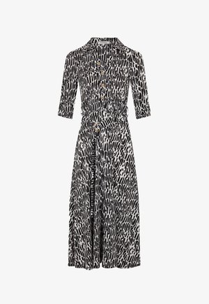 Vestido de estampado en blanco y negro con botones en el frente, cuello, mangas de tres cuartos, cintura ceñida con cinturón y tejido texturizado.
