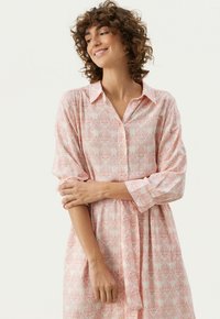 Robe longue à manches longues rose avec un col à pressions. Présente un motif floral, un tissu doux et une coupe décontractée avec un détail noué à la taille.