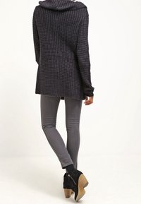 Huvtröja med struktur i mörkgrå oversized stil, ihopparad med grå smala jeans och svarta ankelstövlar med träklack.