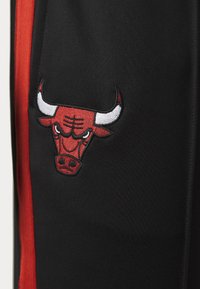 Crne atletske kratke hlače imaju istaknuti crveni i bijeli izvezeni logo Chicago Bullsa s lijeve strane. Dizajn uključuje crvene bočne pruge.