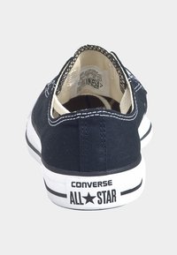 Baskets basses en toile bleu marine avec semelle en caoutchouc blanche, logo étoile à contour noir et surpiqûres blanches contrastantes le long des bords.