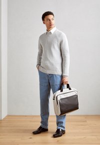 Grauer Pullover, blaue Jeans, schwarze Lederschuhe. Trägt eine grau-schwarze zweifarbige Aktentasche mit oberen Griffen. Glatte Textur, modernes Design.