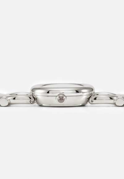 Silverfärgad metallklocka med en rund kappa och en slät bezel. Har en enda krona och länkar på armbandet, som visar en polerad yta.