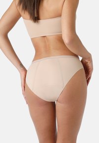 Perizoma seamless beige con una cintura ampia e una texture liscia, caratterizzato da dettagli di cucitura sottili e un design a gamba alta.