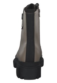 Botas de tobillo beige con un panel elástico negro, cuero texturizado y una suela gruesa negra. Cuenta con una cremallera lateral para facilitar su puesta.