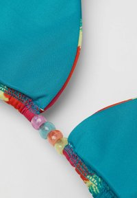 Tyrkysový bikiny vršek s živými tie-dye akcenty, bezšvová konstrukce a barevné korálkové kování spojující košíčky.