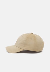 Beige corduroy baseball cap with a curved visor, stitched detailing, and ventilation holes on the top. No visible logos or patterns.