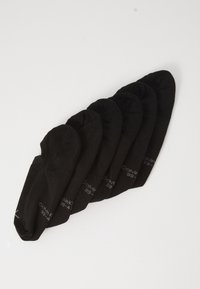 Sechs Paare schwarze, unsichtbare Socken mit kleinen weißen Texten, diagonal gestapelt auf einem weißen Hintergrund.