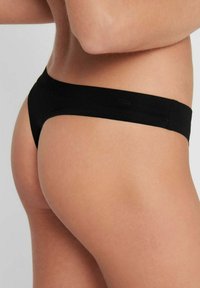 Tanga negro con una textura suave, cobertura mínima y una cinturilla delgada. Presenta un diseño elegante y minimalista.