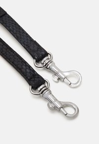 La sangle noire texturée présente un motif serpent avec des fermoirs et un matériel en métal de couleur argentée. La finition lisse de la sangle complète le design.