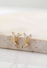 Orecchini in tono oro caratterizzati da gemme trasparenti a forma di marquise e rotonda, progettati con una delicata forma a farfalla e dettagli pendenti.