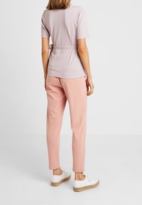 Top de rayas en color púrpura claro con mangas cortas, cintura ceñida, combinado con pantalones ajustados rosas y zapatillas de plataforma blancas.
