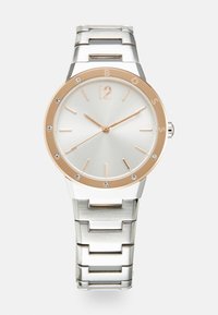 Silberne Edelstahl-Uhr mit polierter Oberfläche, roségoldener Lünette, weißem Zifferblatt, goldenen Stundenmarkierungen und Kristallakzenten rund um das Zifferblatt.