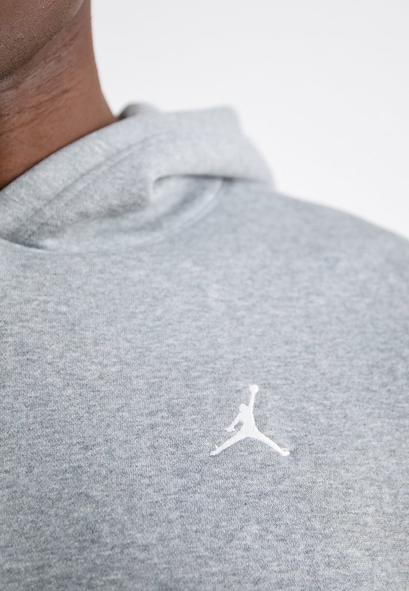 Grauer Baumwoll-Hoodie mit glatter Textur. Mit einem weißen Jumpman-Logo auf der Brust und einer Kordelzugkapuze.