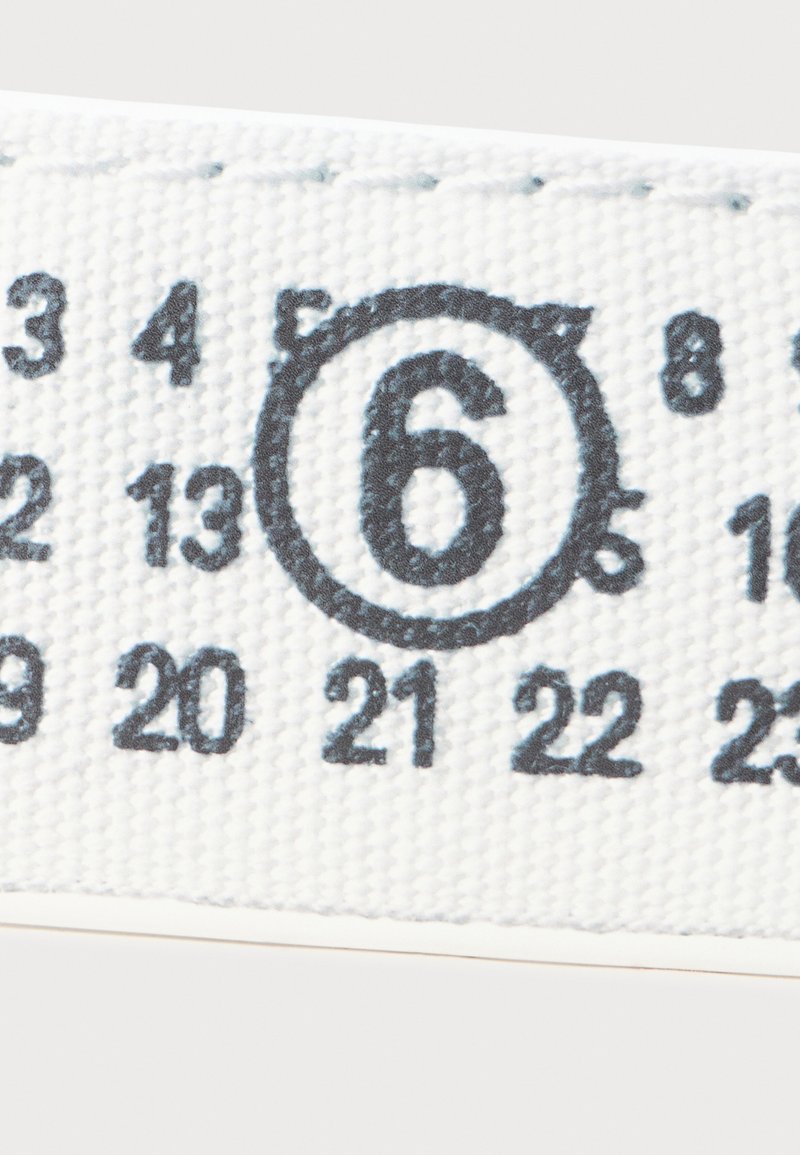 White fabric tape measure marked with black numbers. Notable detail: the number 6 is circled, with various other numbers visible around it.