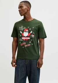 Camiseta de algodón verde con un gráfico de Santa con gafas de sol, acentos rojos, renos y texto navideño. Diseño de mangas cortas y cuello redondo.