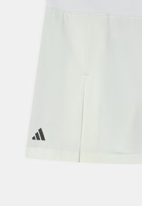 Pantalones cortos de color claro hechos de una tela suave, con un logo negro de Adidas y aberturas laterales para mayor movilidad.