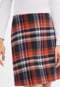 Mini spódniczka w kratę w kolorach pomarańczowym, granatowym, białym i czarnym, wykonana z teksturowanej tkaniny o prostej sylwetce.