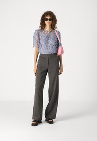 Light blue lace top with puff sleeves, paired with gray pinstripe wide-leg pants. Accessorized with a pink handbag and black platform sandals.