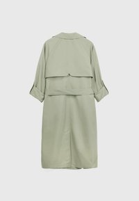 Trench coat verde claro con una solapa en la parte posterior, cinturón y mangas recogidas. Textura suave, diseño hasta la rodilla y detalles minimalistas.