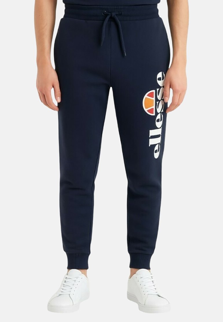 Pantalon de survêtement bleu marine avec taille élastique et cordon de serrage ; présente un logo "ellesse" blanc et un accent circulaire multicolore sur la hanche.