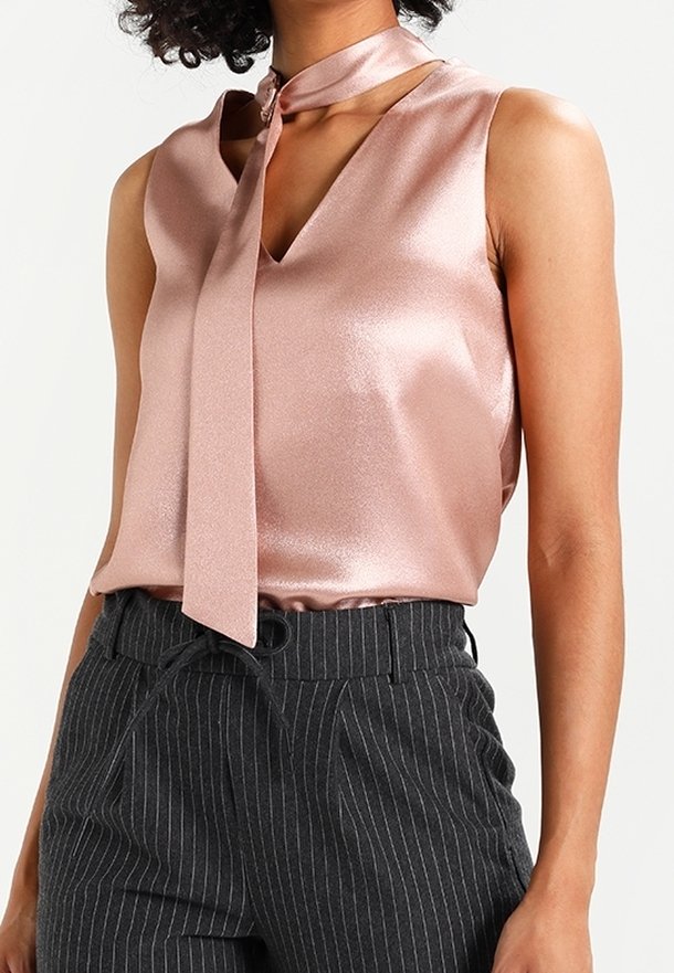 Satin rosa utan ärmar med V-ringning och en knytning vid kragen, tillsammans med kol-grå randiga högmidjade byxor.