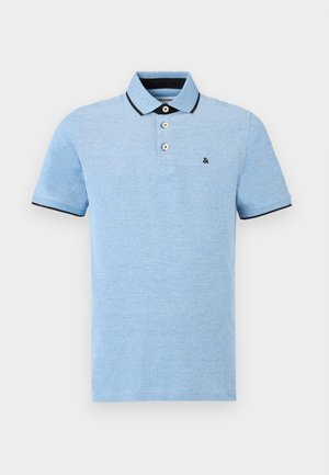 Lyseblå polo-skjorte laget av bomull, med en tre-knapps placket, svart kragekant og en liten brodert logo på brystet.