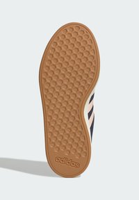 Gummisula för sneakers med ett bikakemönster, brun färg med vit kant. Dekorerad med tre rosa ränder; präglad logotyp.