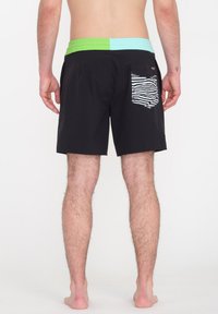 Bañador negro con una cintura verde y azul. Cuenta con un bolsillo trasero con un diseño de rayas de cebra. Material suave y ligero.