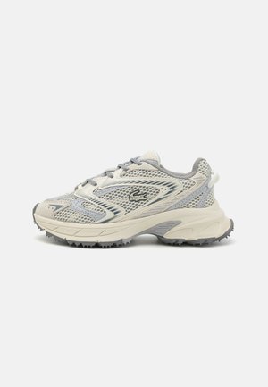 Scarpe da corsa Lacoste in grigio chiaro con tomaia in rete, suola in gomma e dettagli testurizzati. Presentano un logo prominente sul lato.