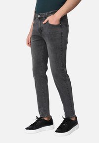 Jeans in denim grigio con vestibilità slim, caratterizzati da un classico design a cinque tasche e zip. Abbinati a sneakers nere.