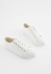 Vita sneakers med en slät läderfinish, rund tå, guldögon, och platta snören. Subtila sömdetaljer på sidorna och sulan.